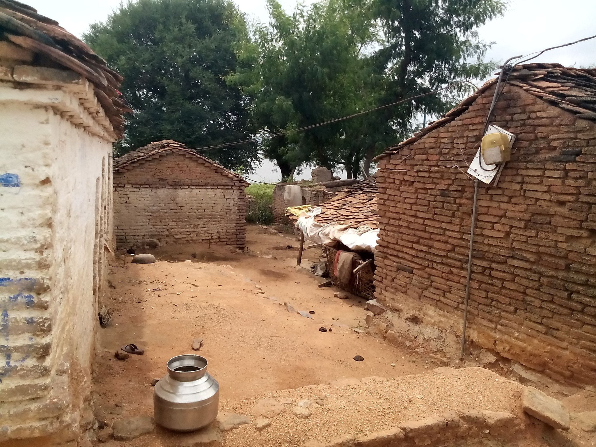 Village lane between brick houses with a steel water pot in the foreground