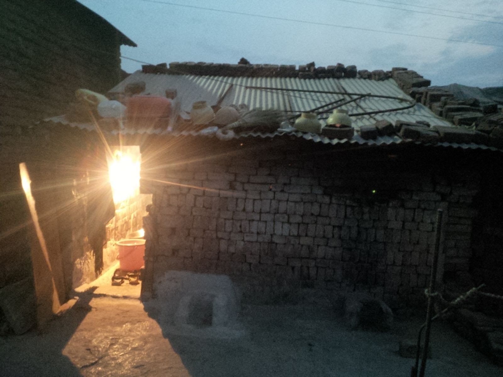 Brick shelter lit by a single bulb at dusk