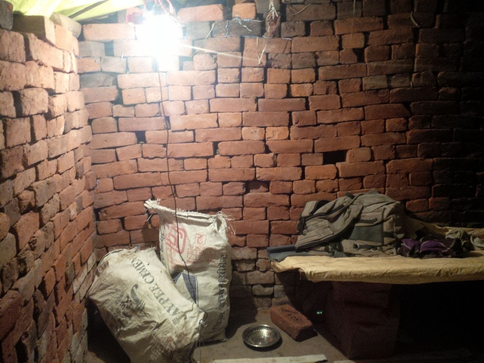 Inside a worker's brick room with sacks and a bed